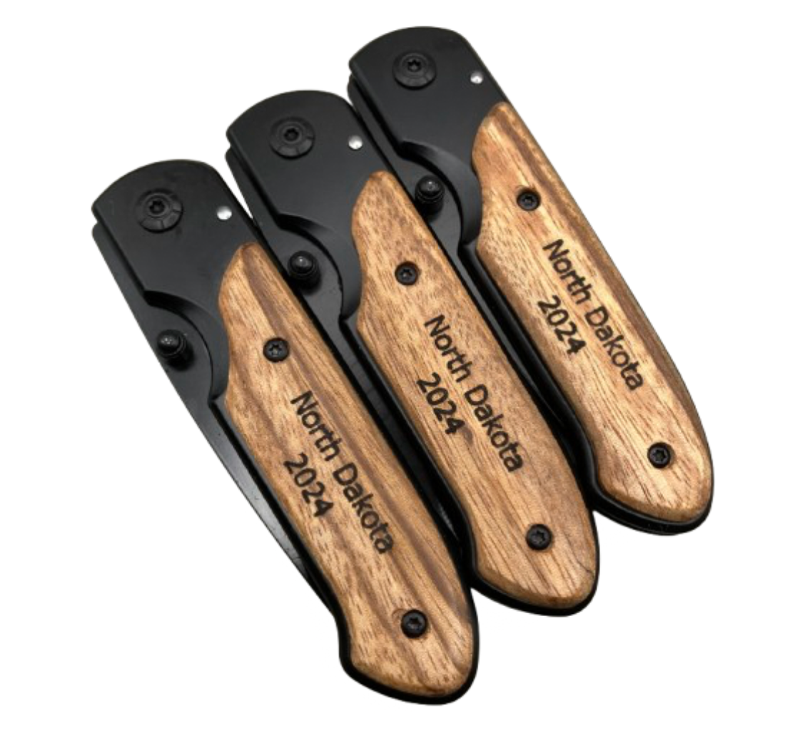 Engraved knife with wood handle, shown closed, designed for a bulk order. The handle features a custom engraving reading 'North Dakota 2024' as a gift for a special occasion.