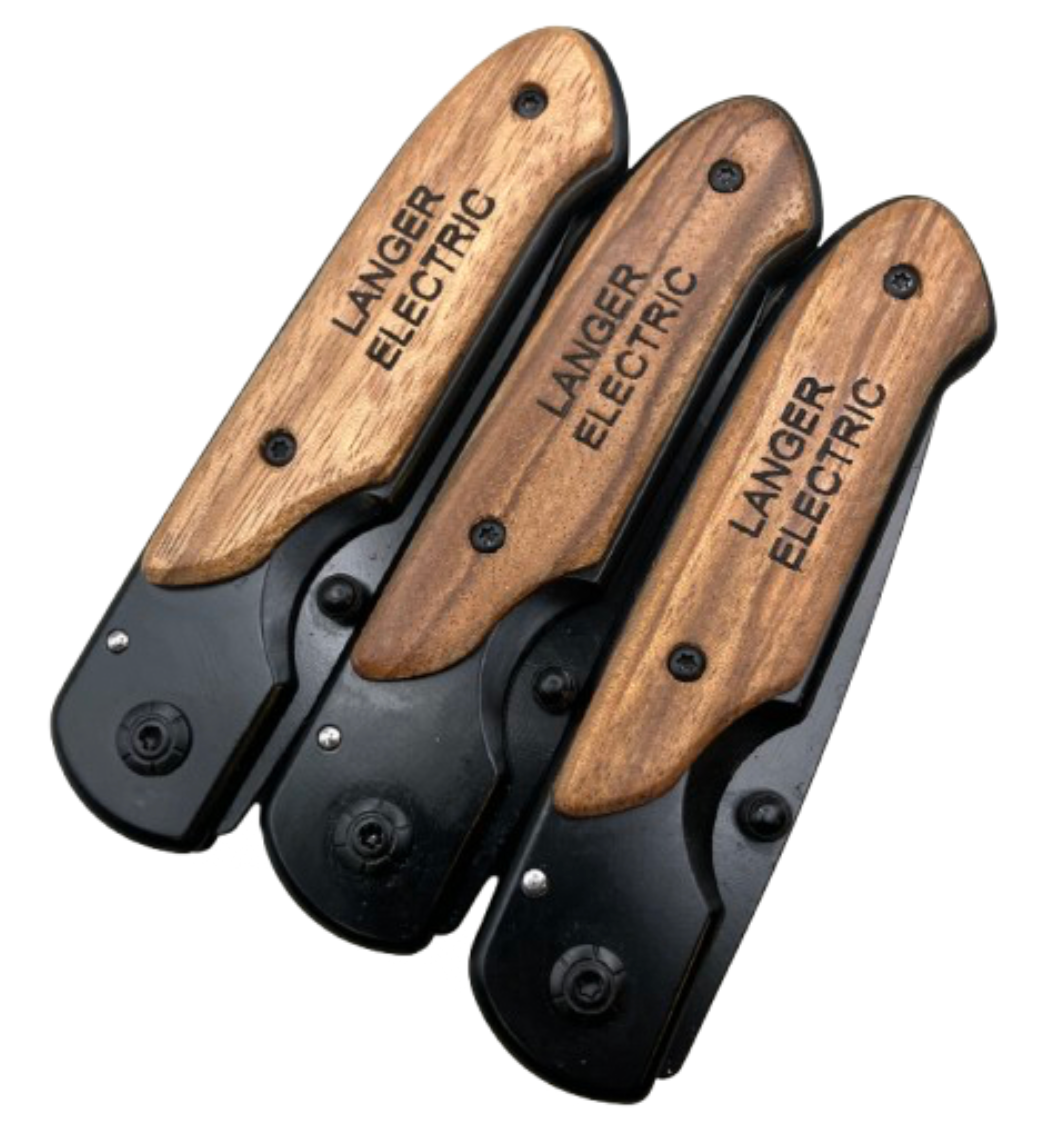 Three engraved knives with wood handle, shown closed, designed for a corporate bulk order. The handle features a custom engraving reading 'Langer Electric' company name on it.