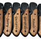 Six engraved knives with wood handle, shown closed, designed for a group christmas gift. The handle features a custom engraving reading 'CJ, Jerry, Gustavo, Gerardo, Raulo, and RFA' on it.